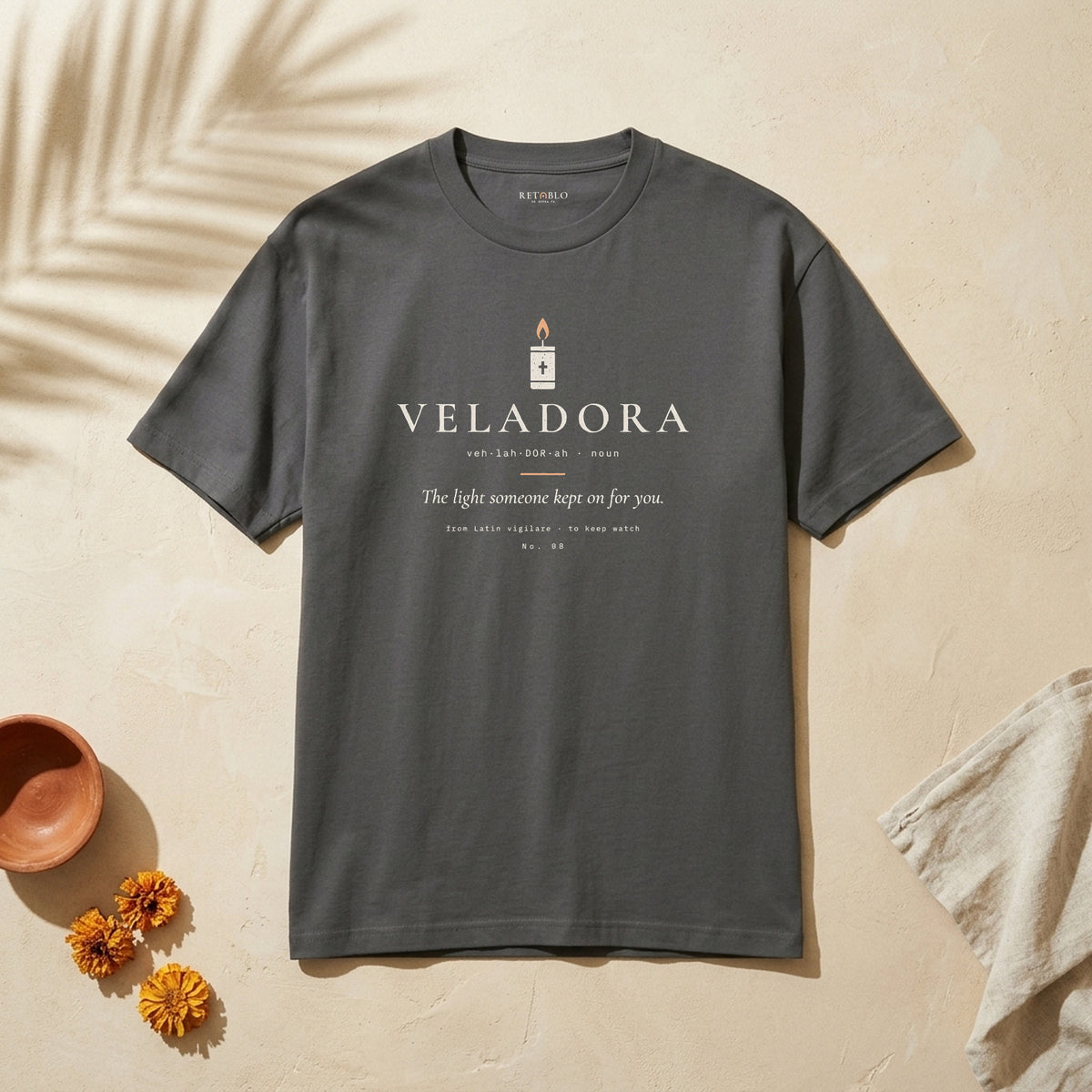 VELADORA Palabra Tee in Faded Black: garment-dyed heavyweight cotton tee printed with a prayer candle and the line “The light someone kept on for you.”