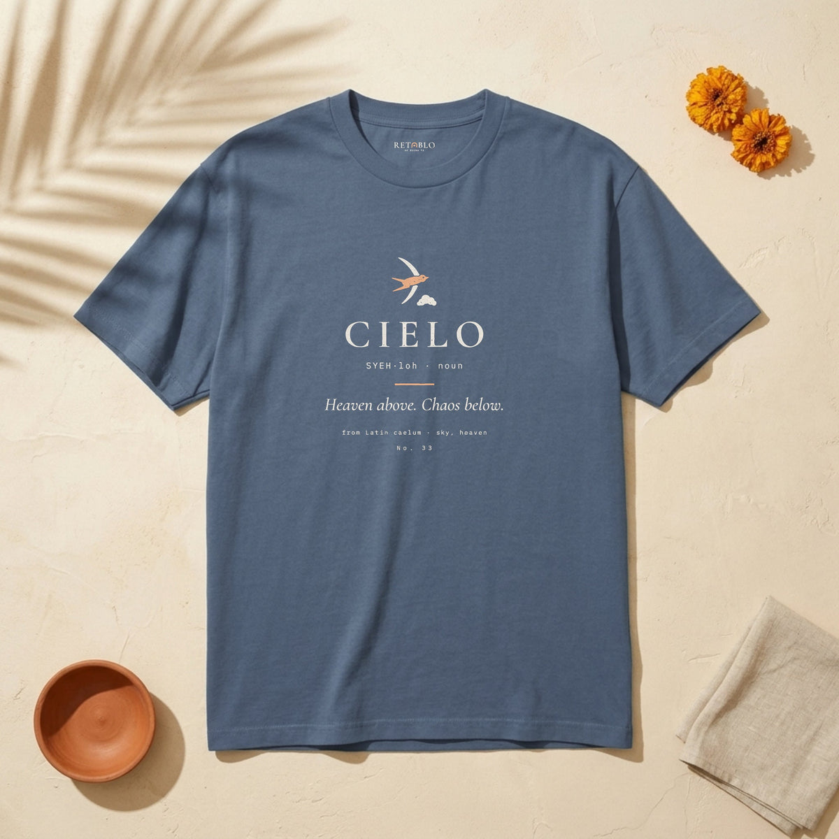 CIELO Palabra Tee in Faded Navy: garment-dyed heavyweight cotton tee printed with a swallow and a cloud and the line “Heaven above. Chaos below.”