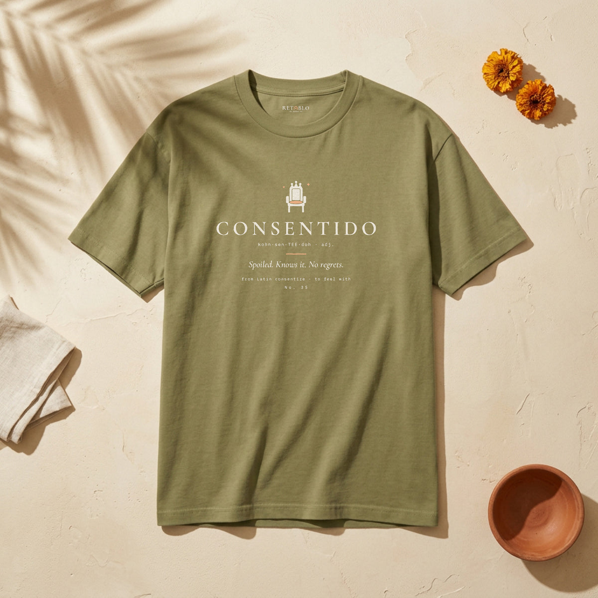 CONSENTIDO Palabra Tee in Faded Army: garment-dyed heavyweight cotton tee printed with a crowned throne and the line “Spoiled. Knows it. No regrets.”